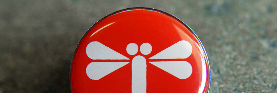 A closeup of enamel pin with JTF logo